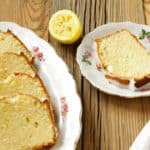 slices of lemon loaf cake on white plates on wooden surface