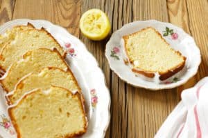 slices of lemon loaf cake on white plates on wooden surface