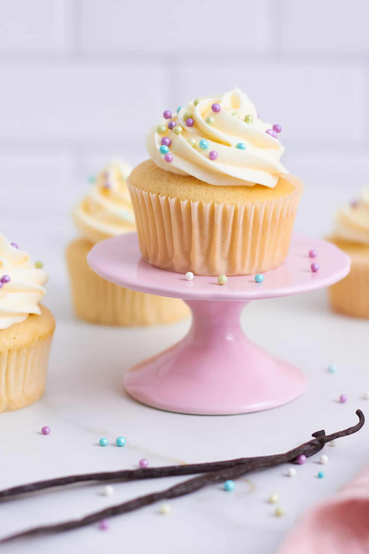 ein vanille muffin auf cupcakeständer mit vanilleschoten in vordergrund