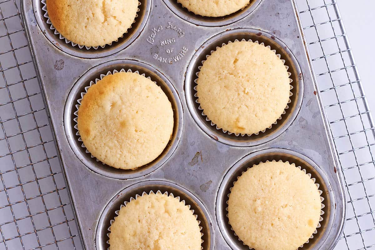 6 baked vanilla cupcakes in a muffin pan